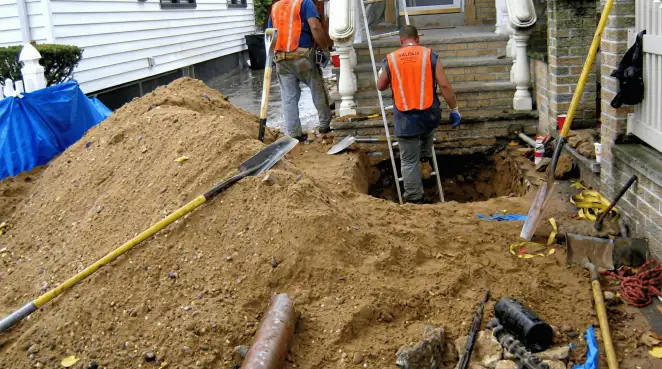 Contractors performing foundation protection and exterior drainage excavation near residential home steps in New Haven, CT
