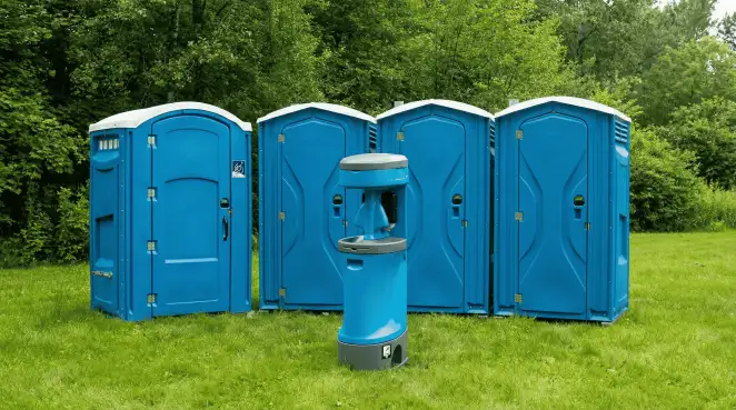 Four blue portable toilets and a matching hand washing station on grass near trees, a common sight at local outdoor events in New Haven, CT